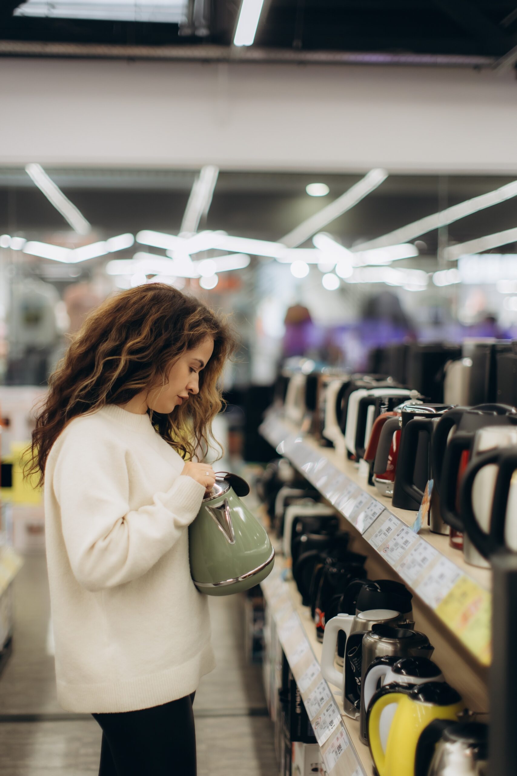 A,Stylish,Young,Woman,Choosing,An,Electric,Kettle,At,An